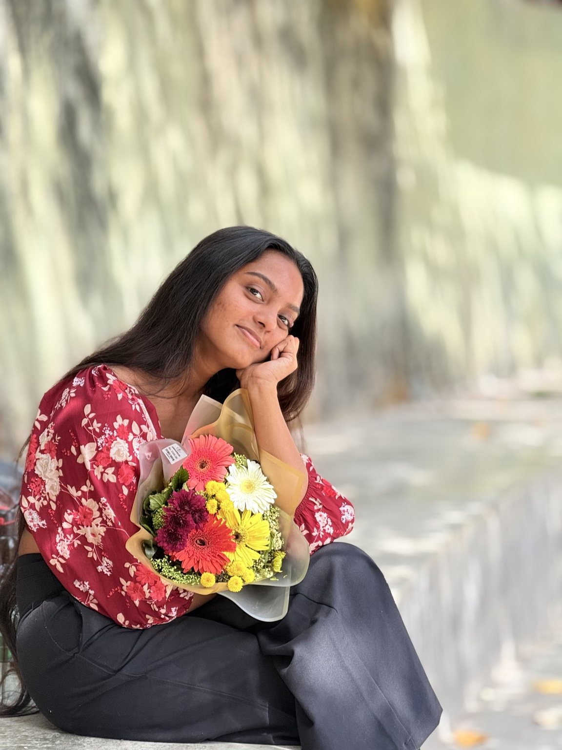 Muthu smiling outdoors among greenery